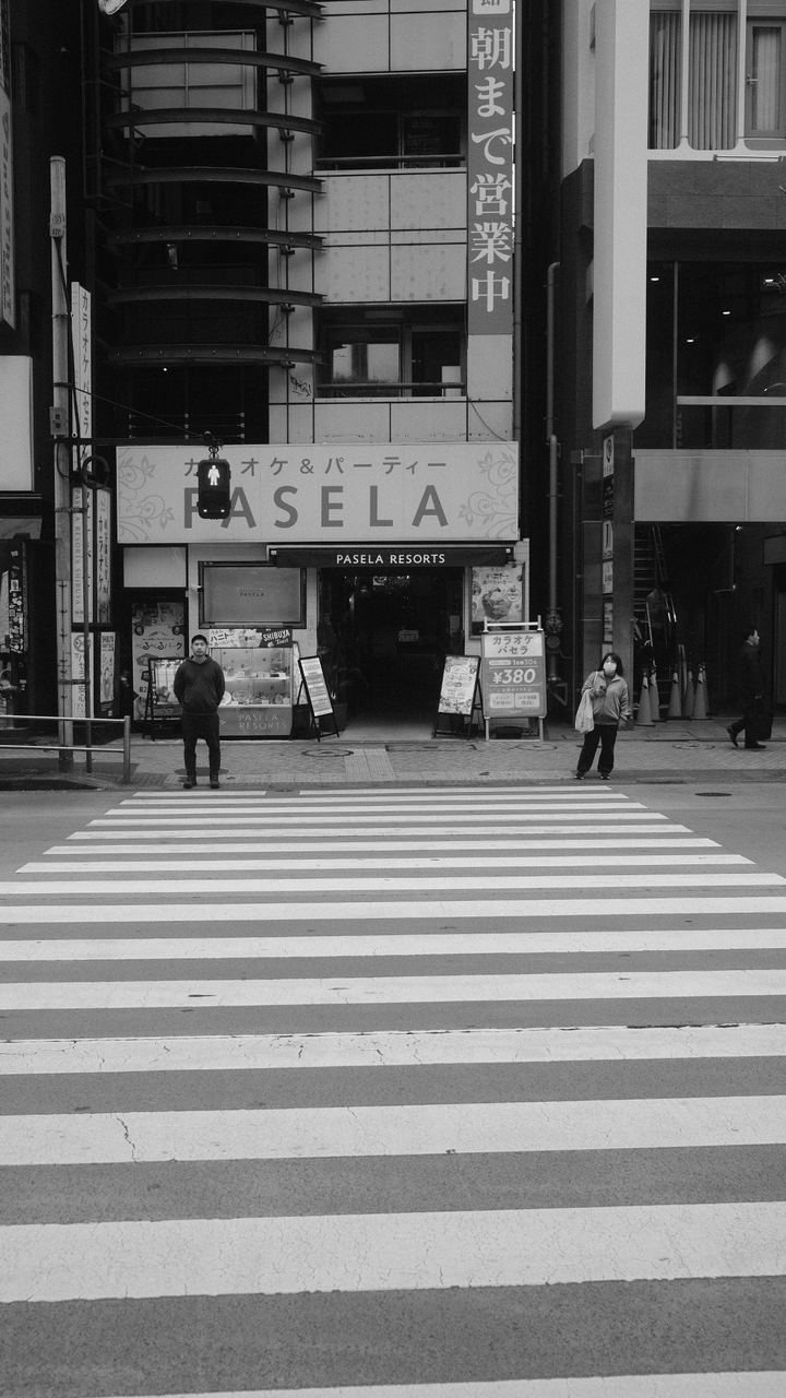A near-empty zebra crossing before a karaoke building, black and white, Shibuya, Tokyo