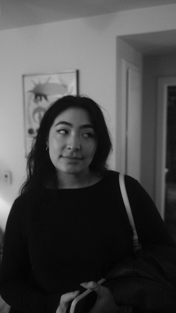 A woman in a black top glancing to the side in soft indoor light, black-and-white portrait