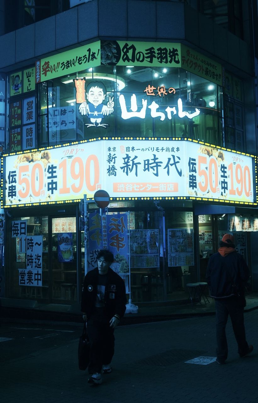 A lone figure passing a glowing izakaya storefront at night, Shibuya, Tokyo