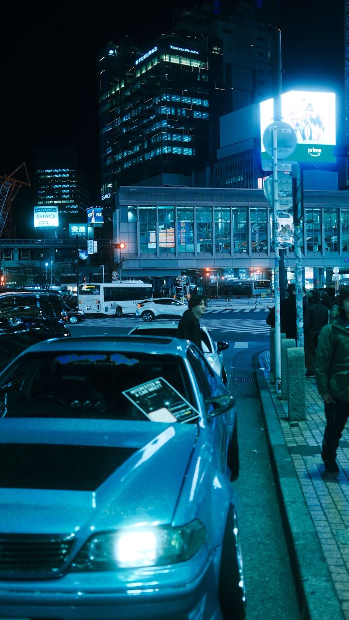 Blue-lit street cars beside Tokyu Plaza at night, Shibuya, Tokyo