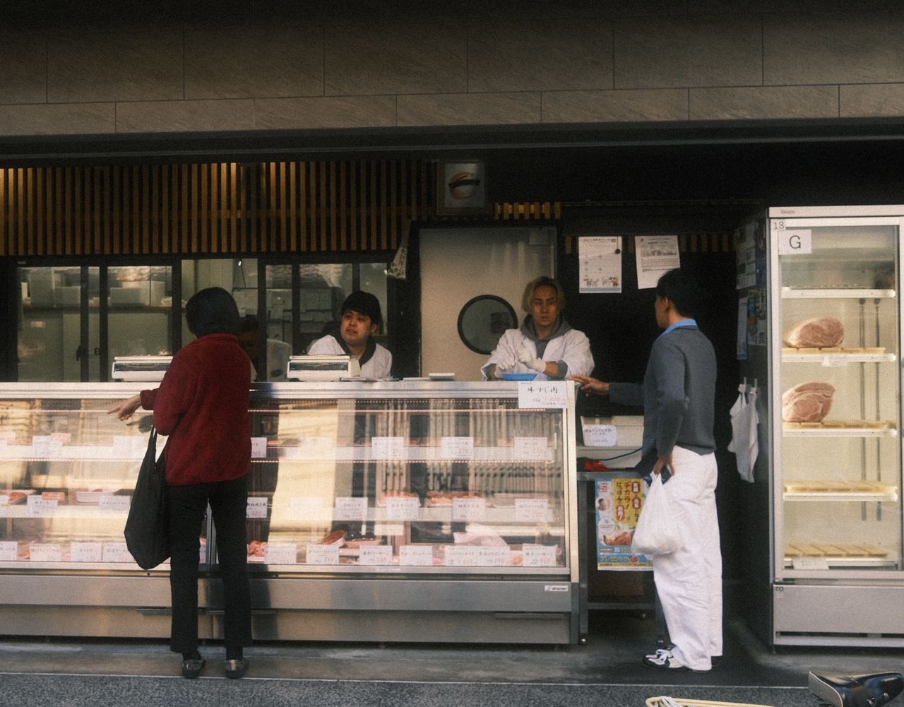Customers at the counter of an open-fronted butcher shop, Tokyo, Japan