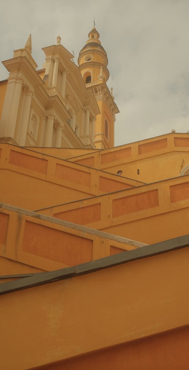 A yellow baroque church tower above sunlit ochre walls, Menton, France