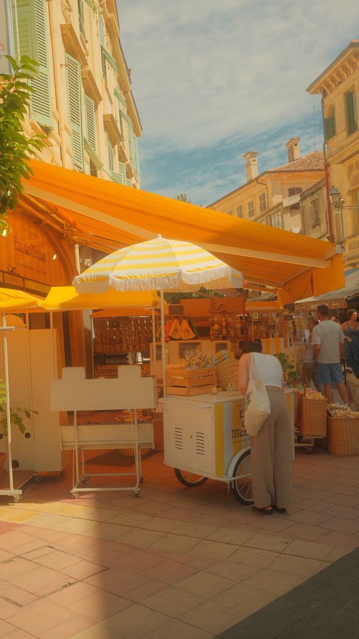 A yellow-awninged perfume stall in warm afternoon light, Menton, France