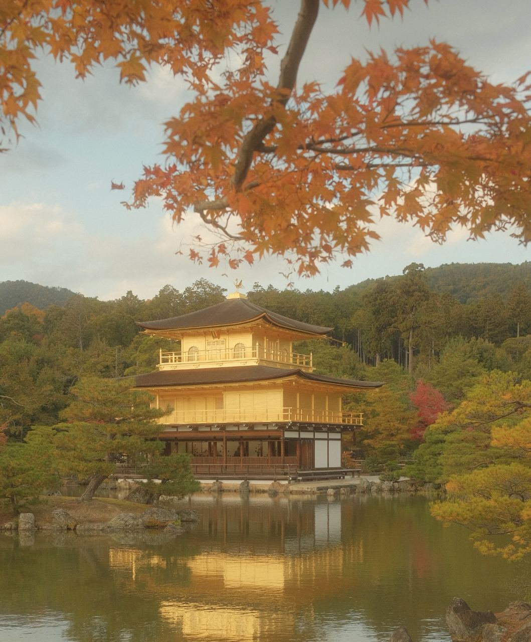 The Golden Pavilion mirrored in its pond and framed by autumn maple, Kyoto, Japan