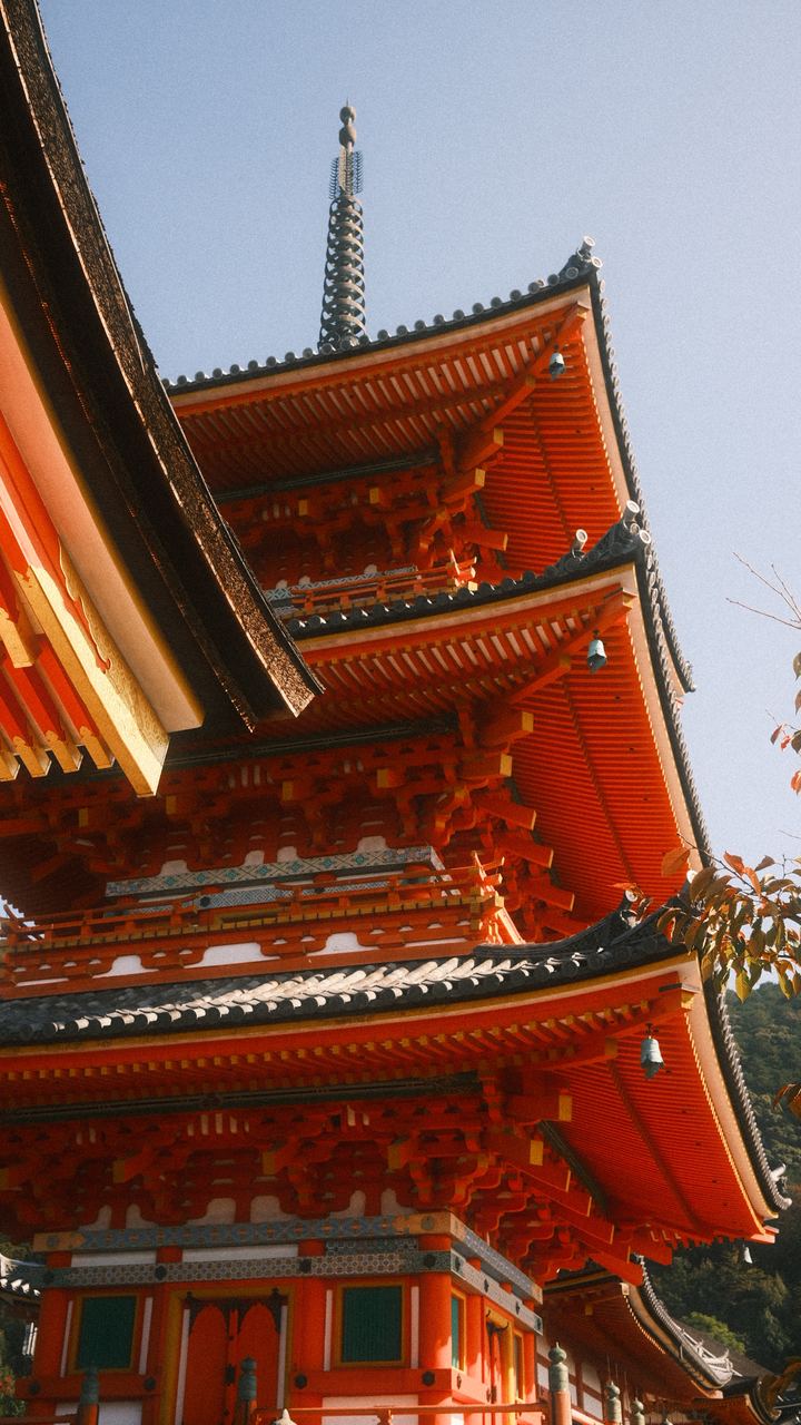 Vermilion tiers of a wooden pagoda against a pale sky, Kyoto, Japan